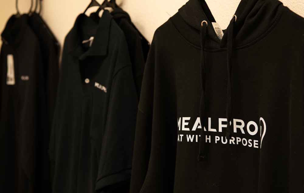 a row of black sweatshirts hanging on a wall