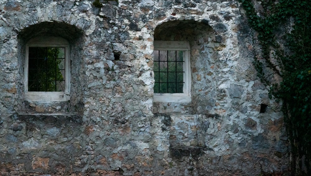 a stone building with three windows and bars