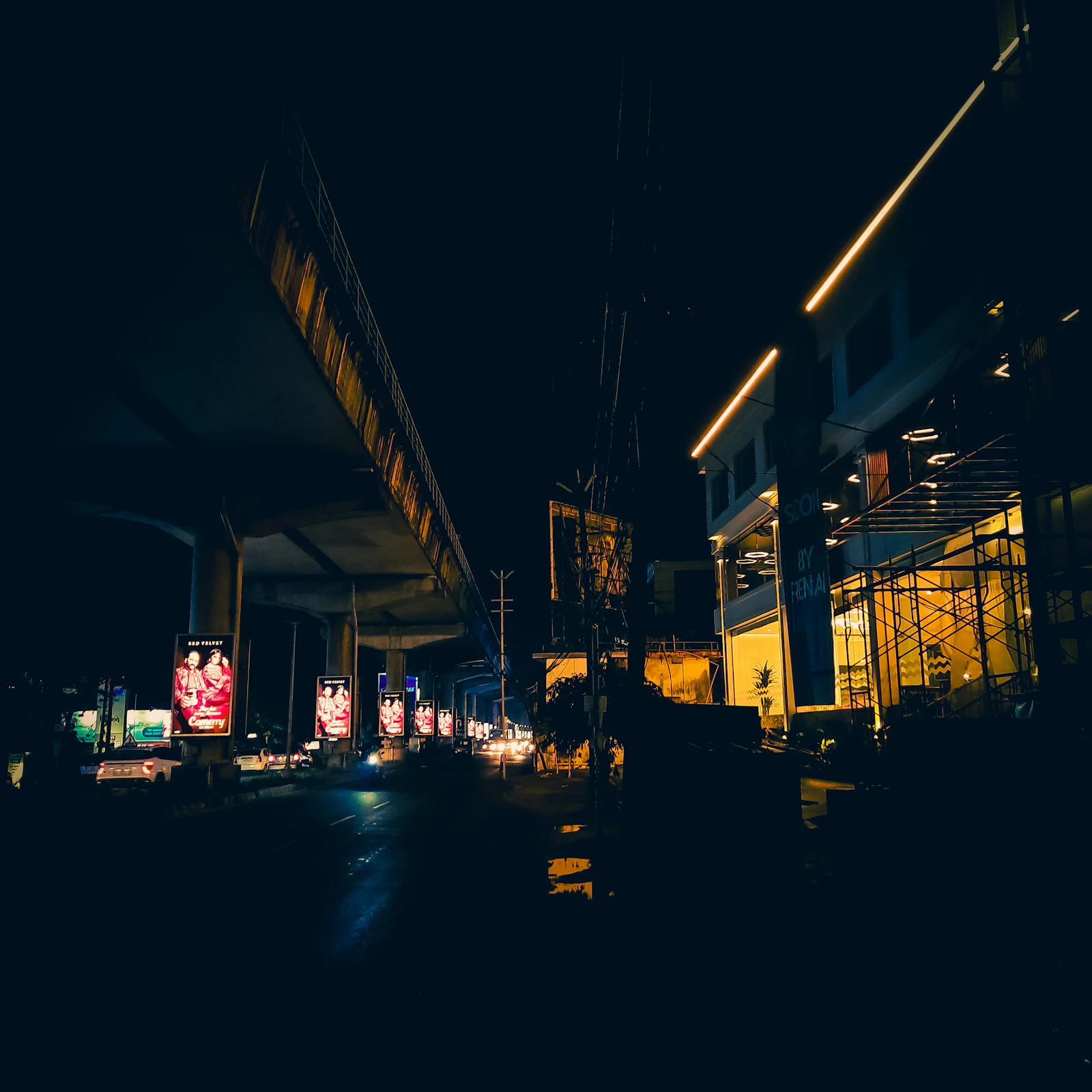 A city street at night with a bridge in the background