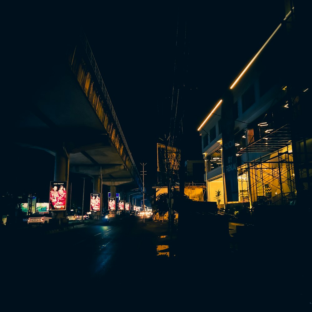 a city street at night with a bridge in the background