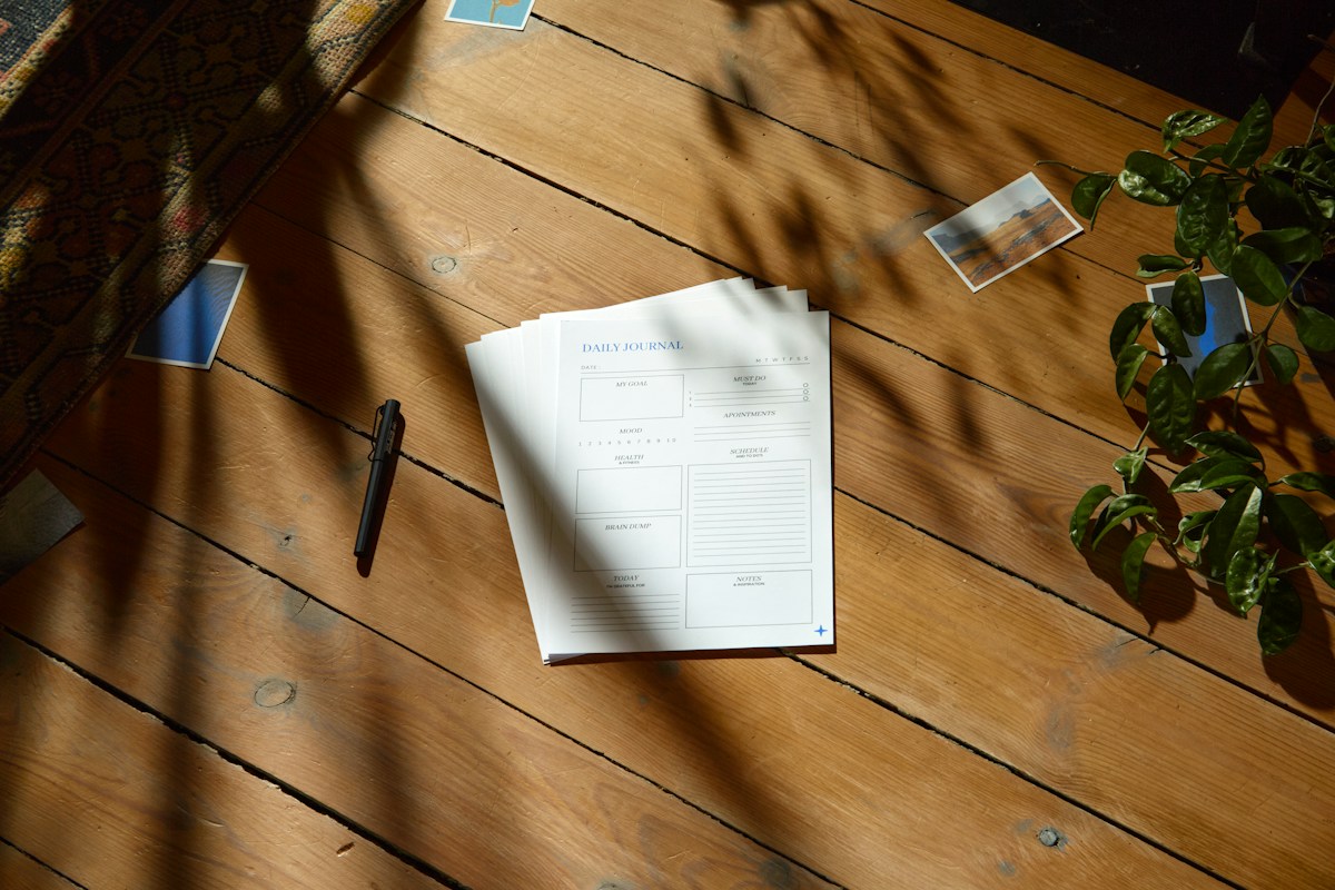 Wooden table with scattered papers and a pen, illustrating school book fair planning and organization tasks.