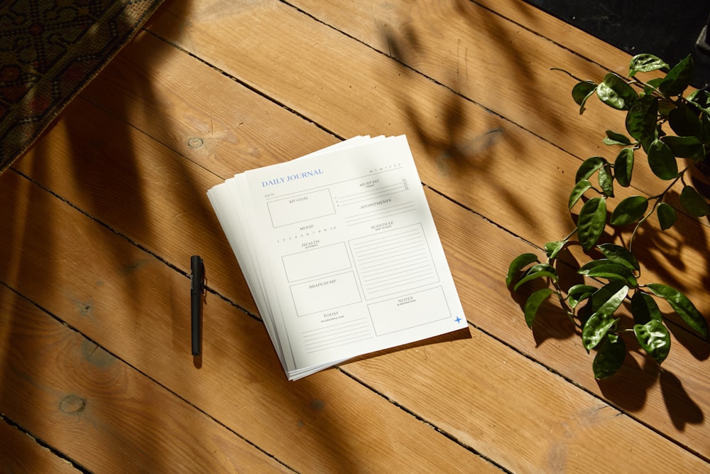 a notepad sitting on top of a wooden table next to a plant