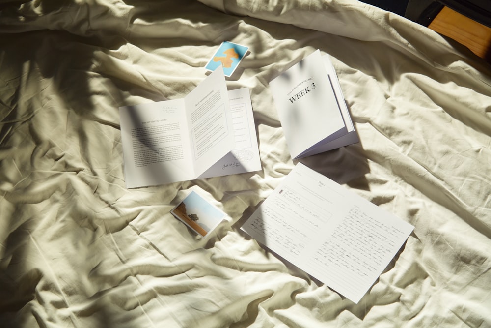 three open books laying on top of a bed