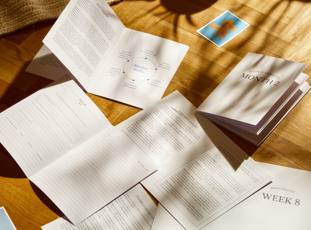 a table topped with lots of papers on top of a wooden table