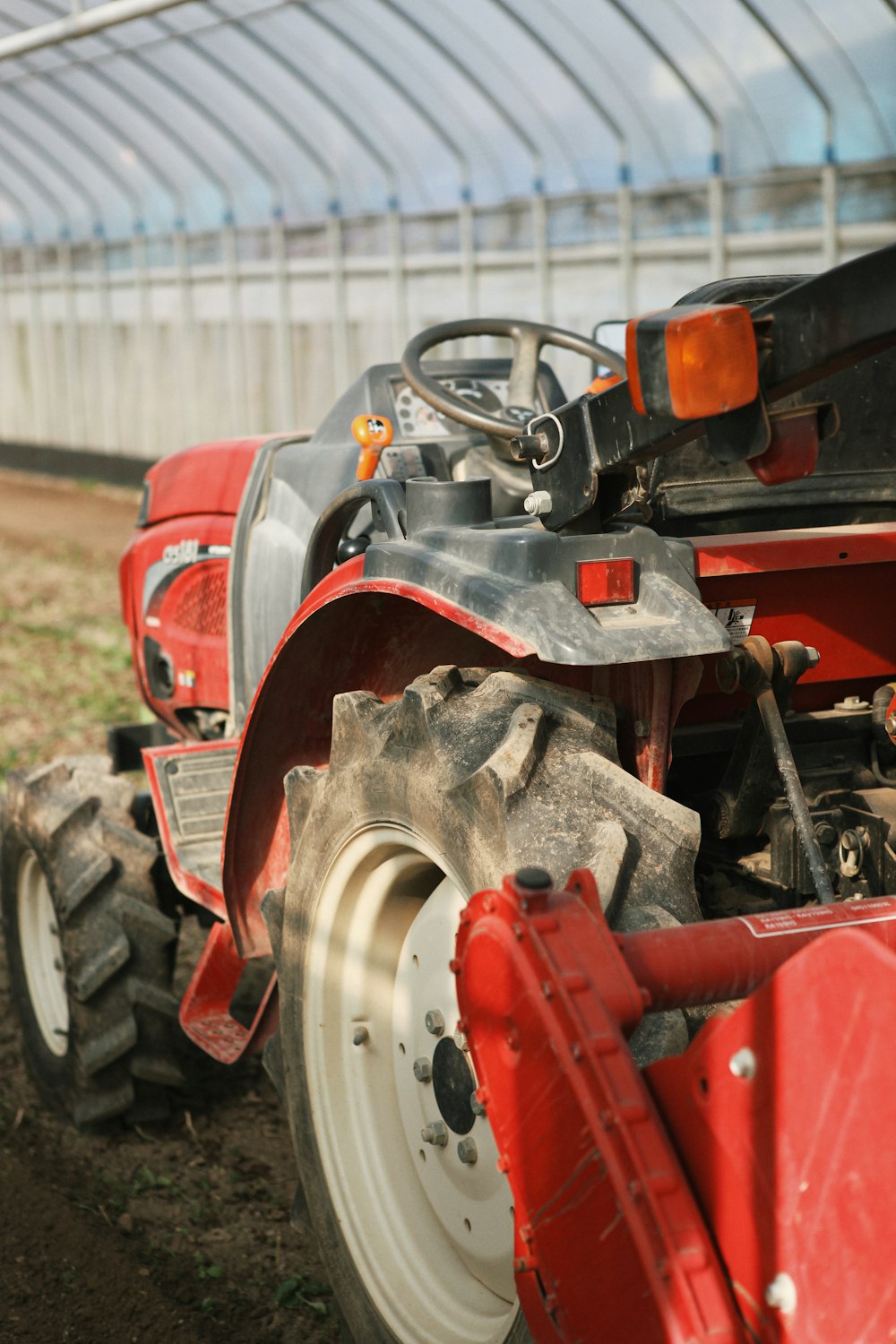 a red tractor parked in front of a greenhouse