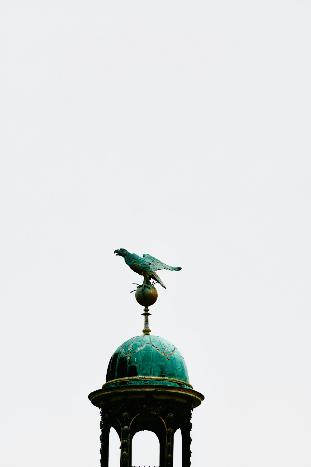 a bird sitting on top of a green dome