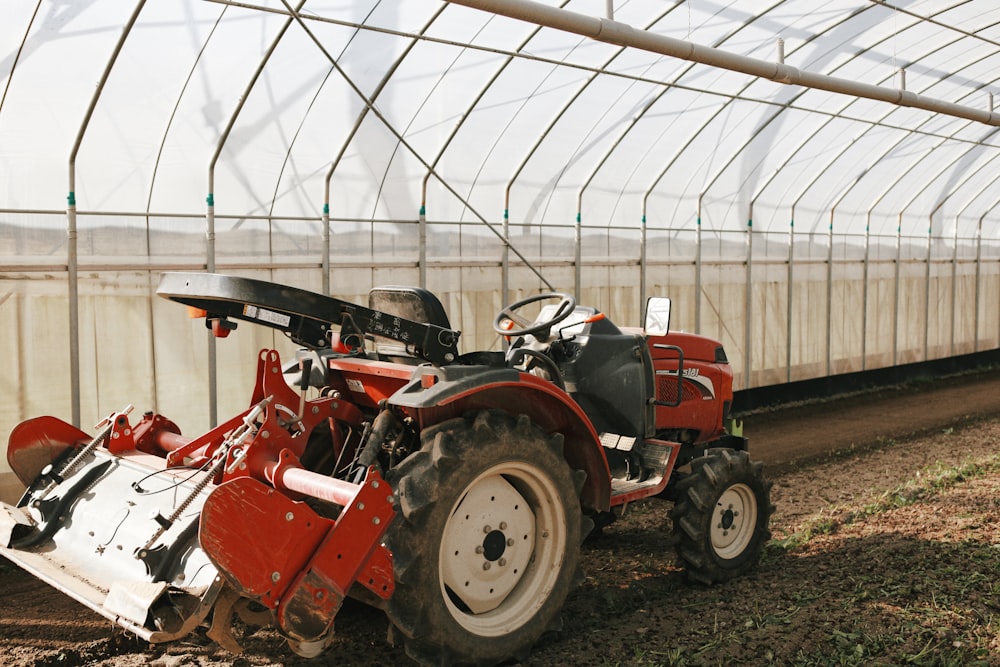 a red tractor is parked in a greenhouse