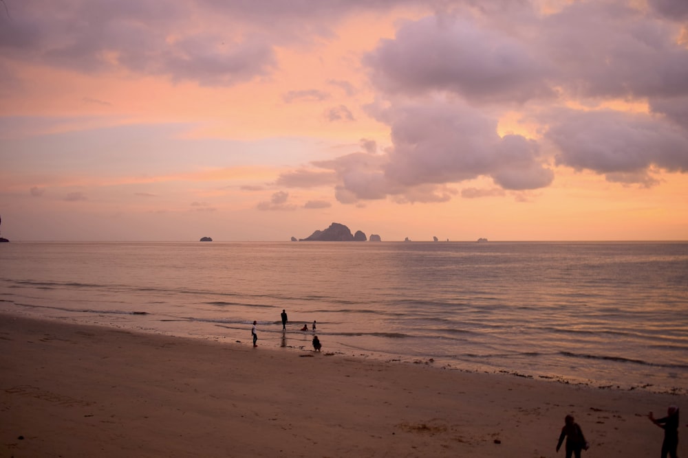 a group of people standing on top of a sandy beach