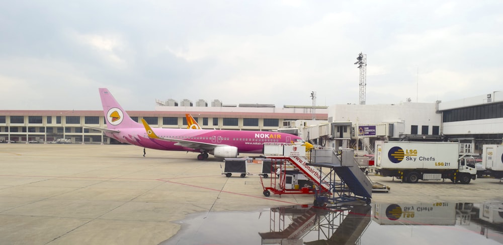 Um avião rosa está estacionado em um aeroporto