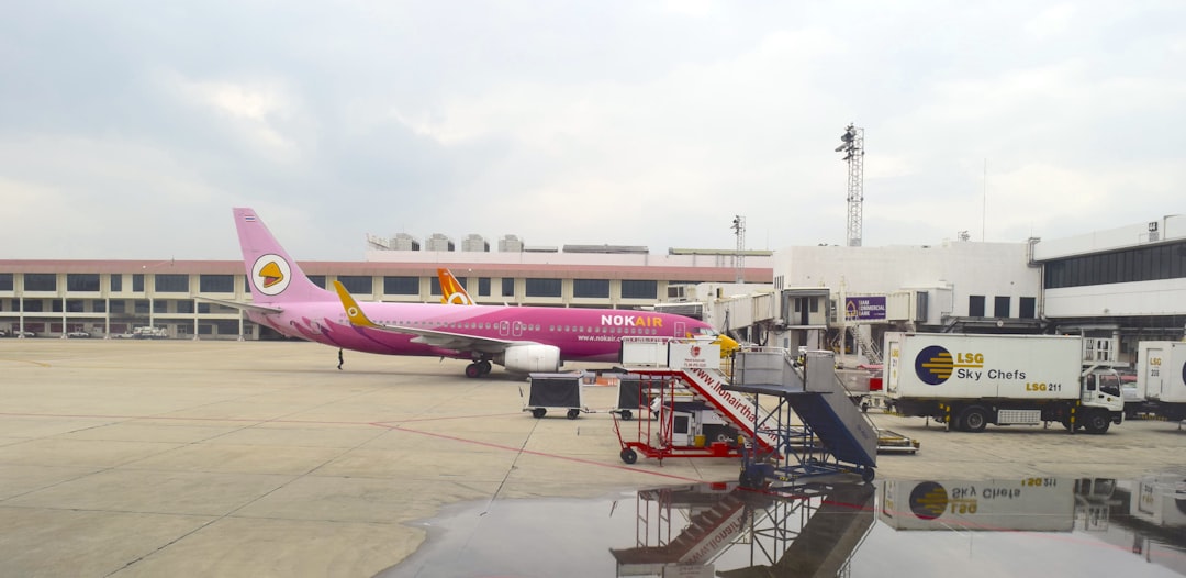 a pink airplane is parked at an airport,