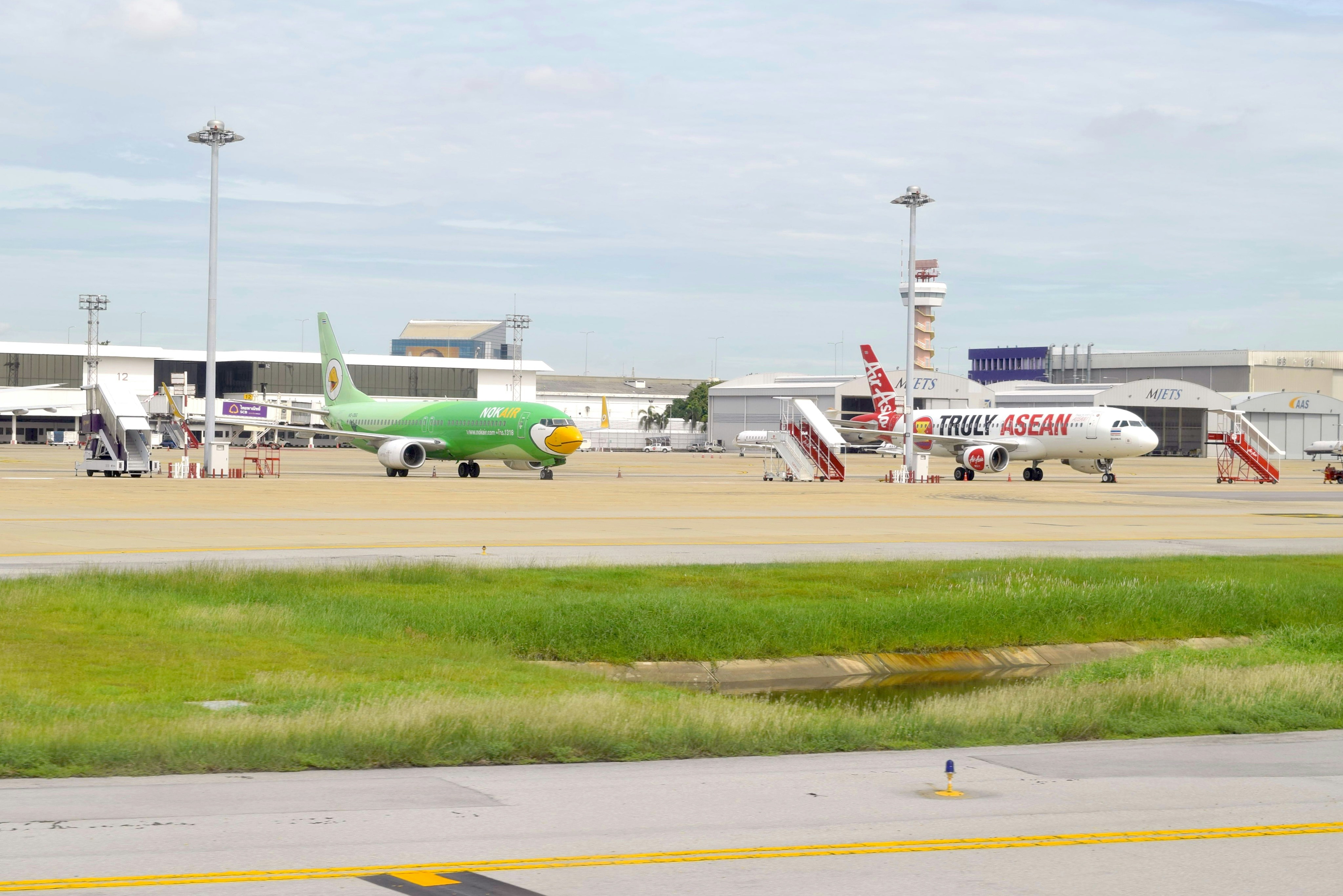 an airport with several planes parked on the tarmac, The 2 aircraft on DMK ramp B737-800 (HS-DBG) and A320-216 (HS-ABE)