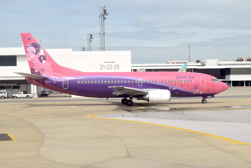 a pink and purple airplane is on the runway