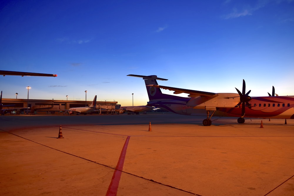 an airplane is parked on the runway at sunset