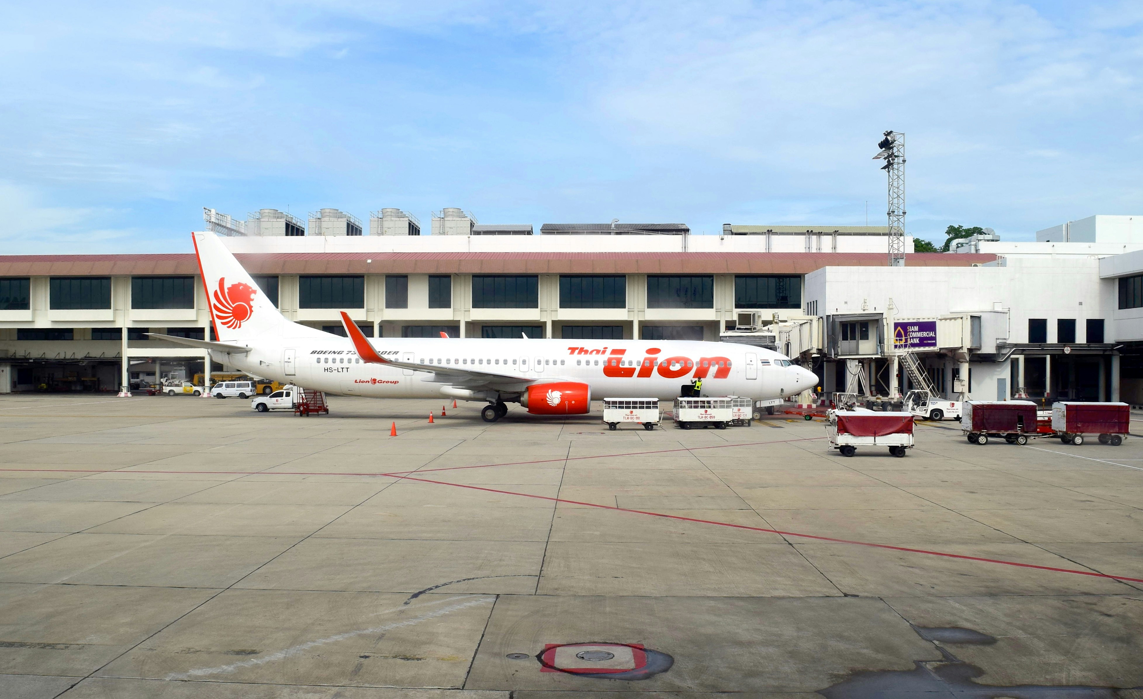 a large jetliner sitting on top of an airport tarmac, Thai Lion Air B737-900ER (HS-LTT) has parked at gate number 42 in Don Mueang airport.