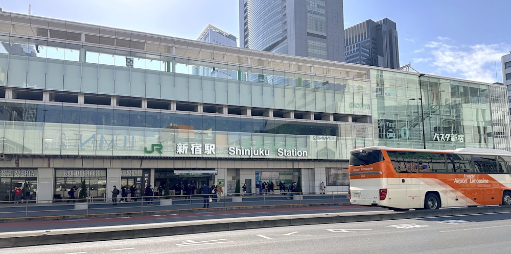 an orange and white bus parked in front of a building