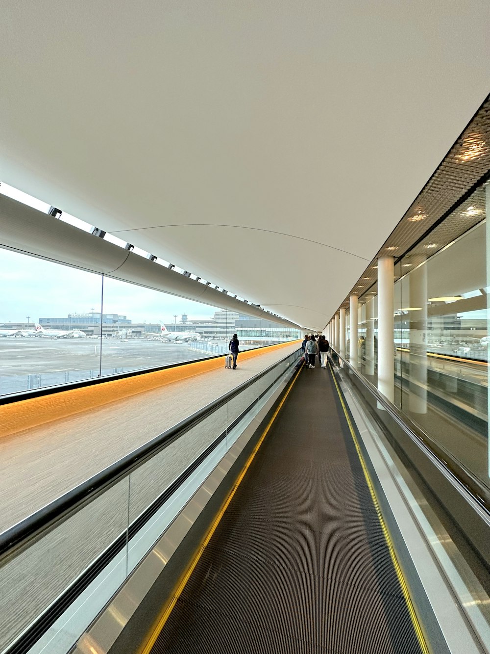 a person walking down a long walkway next to an airport