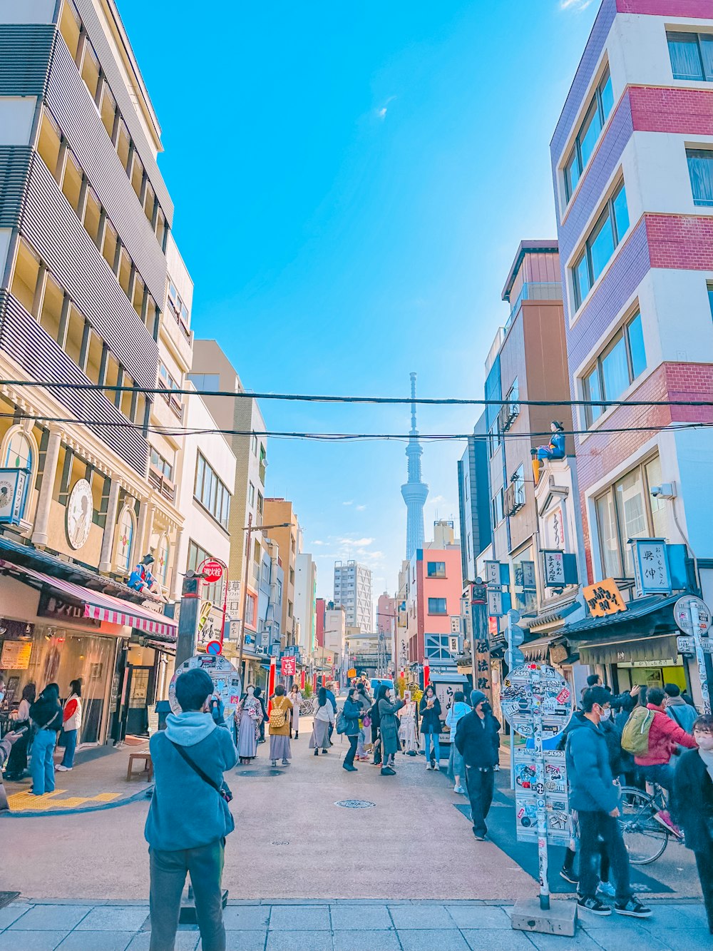 a crowd of people walking down a street next to tall buildings