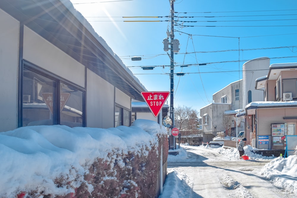 a red stop sign sitting on the side of a snow covered road