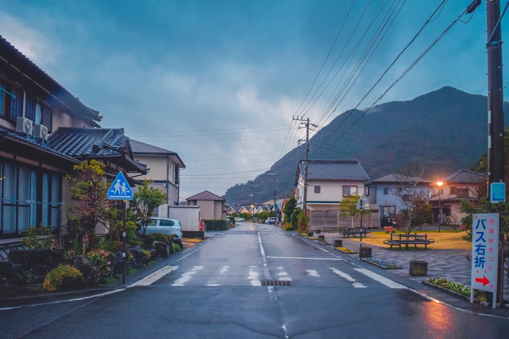 an empty street with houses on both sides and a mountain in the background