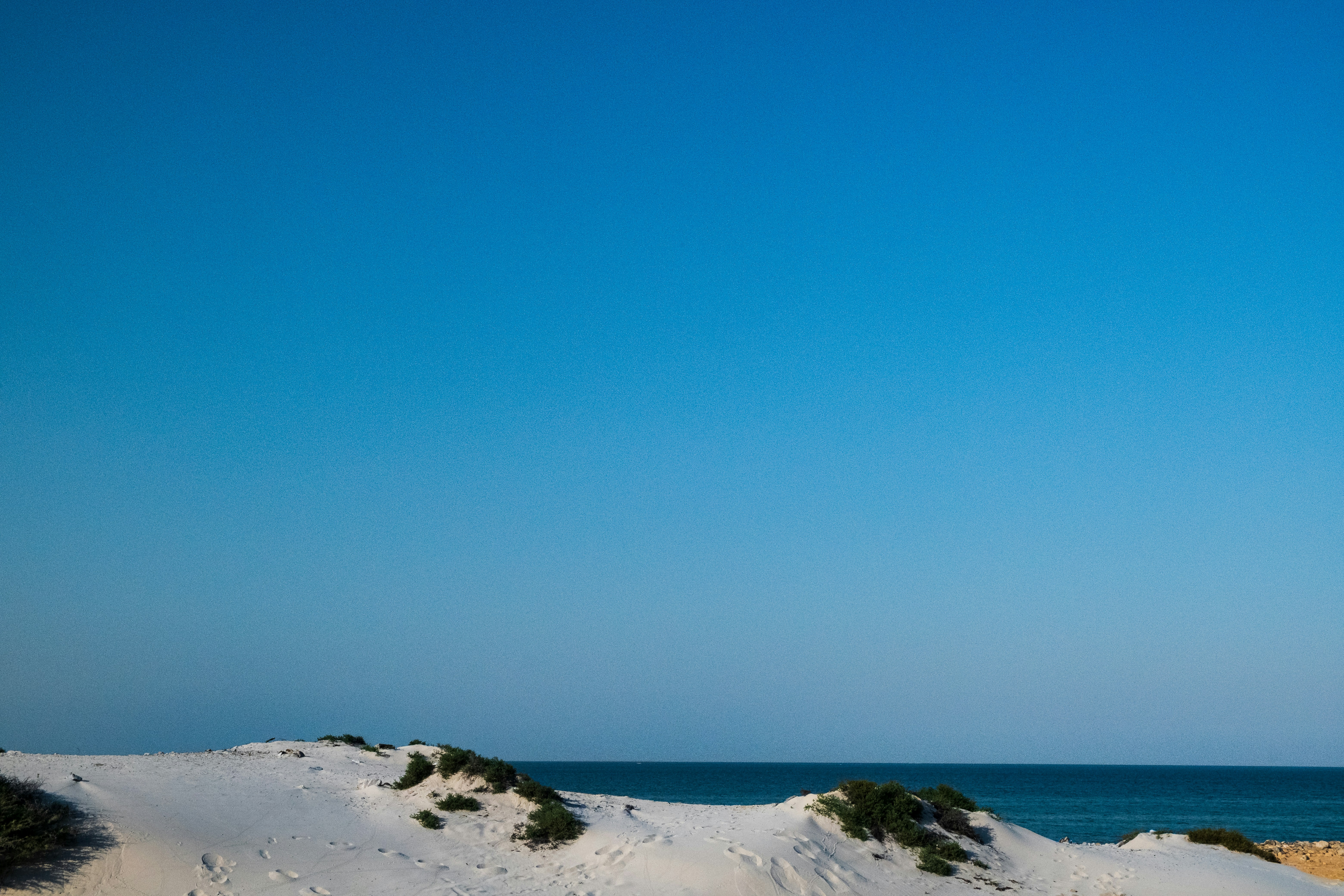 a beach covered in white sand under a blue sky