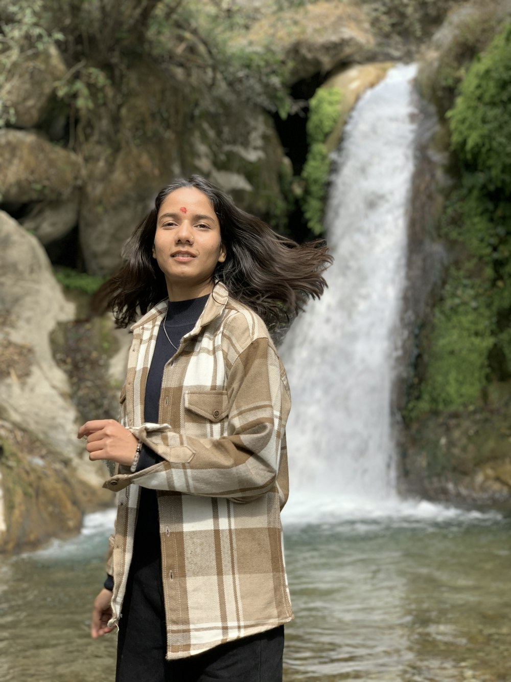 a woman standing in front of a waterfall