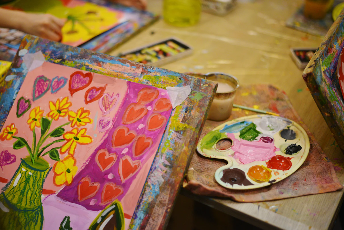 A table laid out with paints, brushes, and paper for an art session