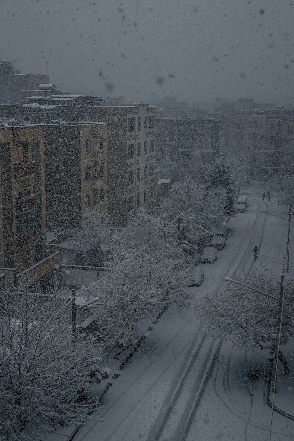 a snow covered city street with buildings and cars