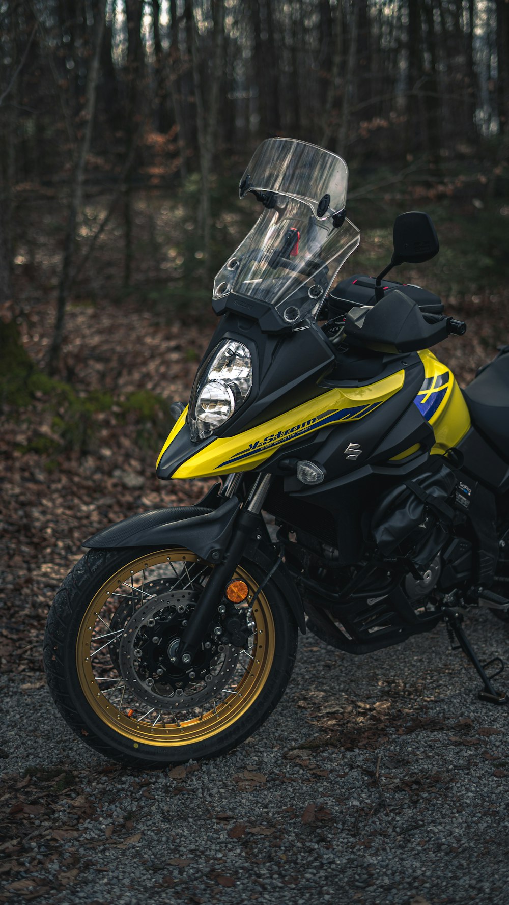 a yellow and black motorcycle parked in a wooded area