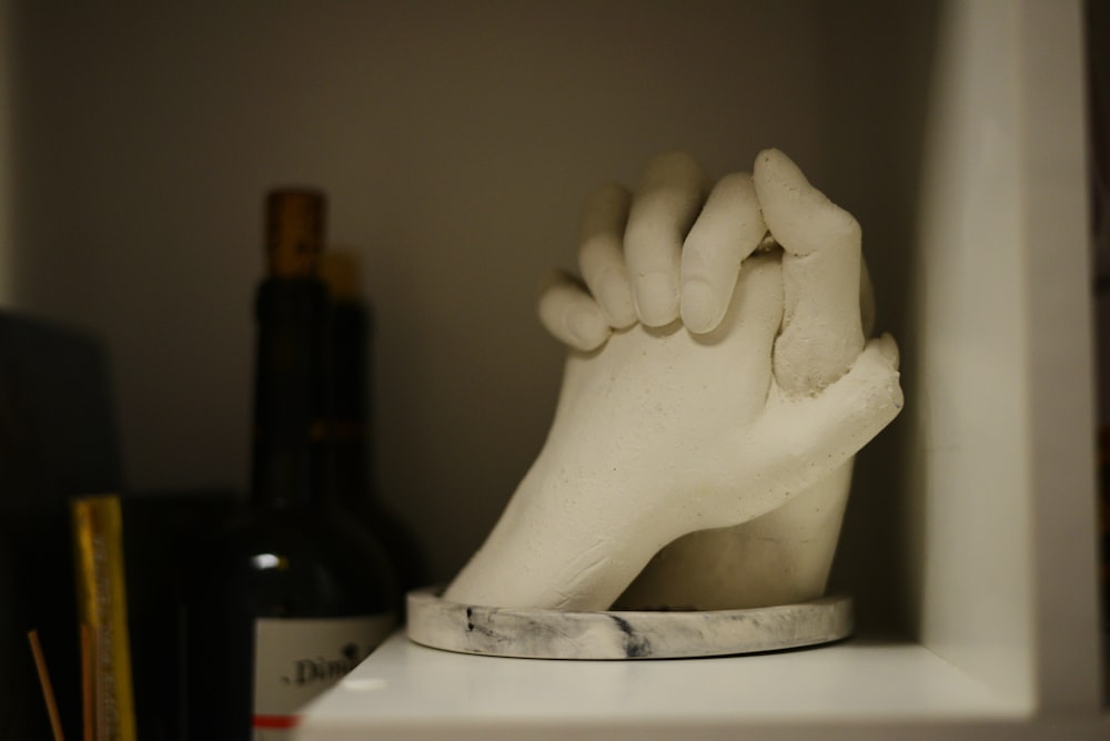 a white sculpture of a hand on a shelf