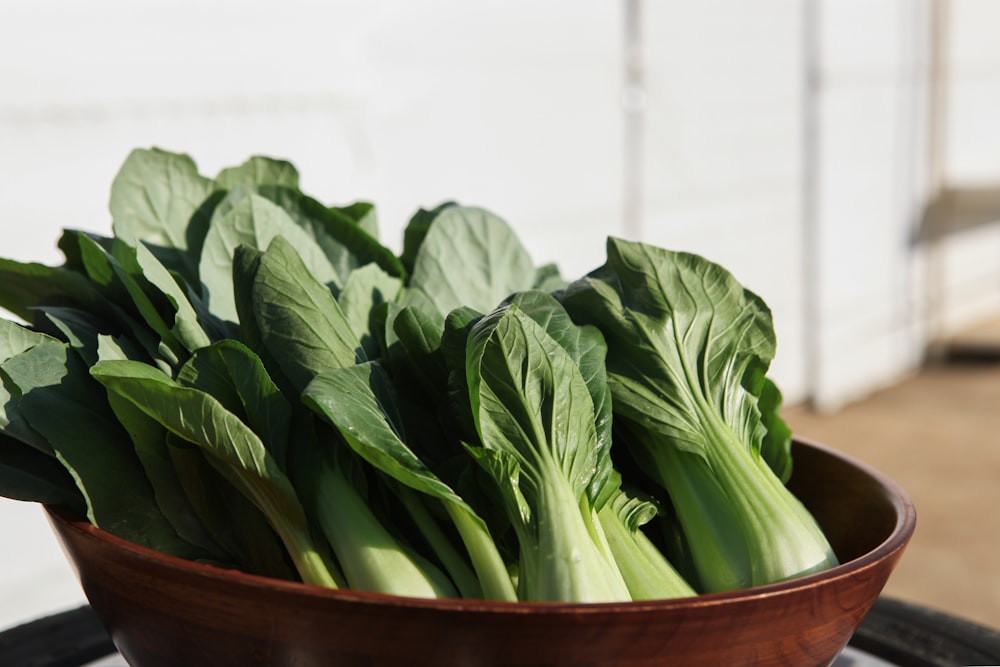 a wooden bowl filled with green leafy vegetables