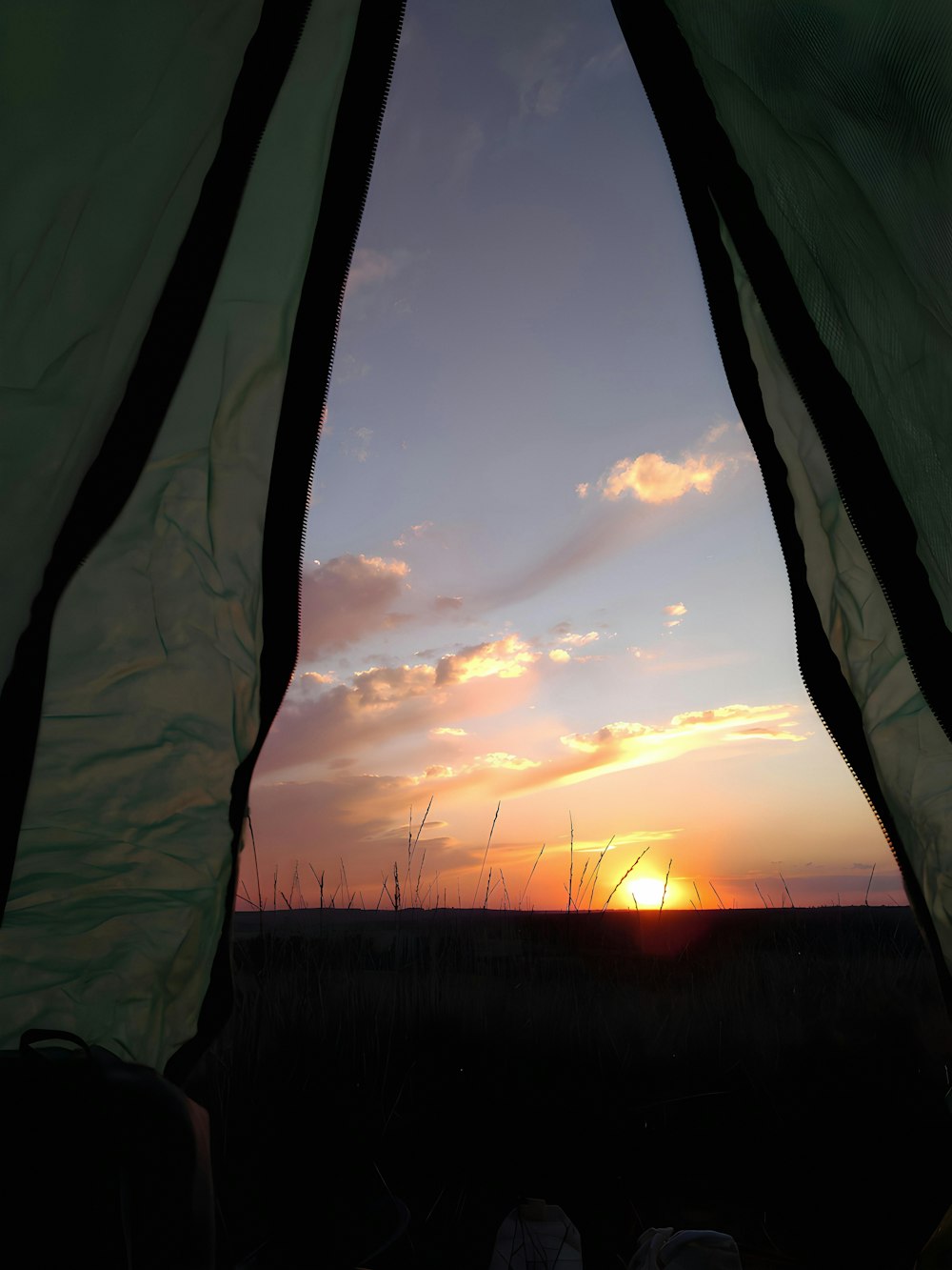 a view of a sunset from inside a tent