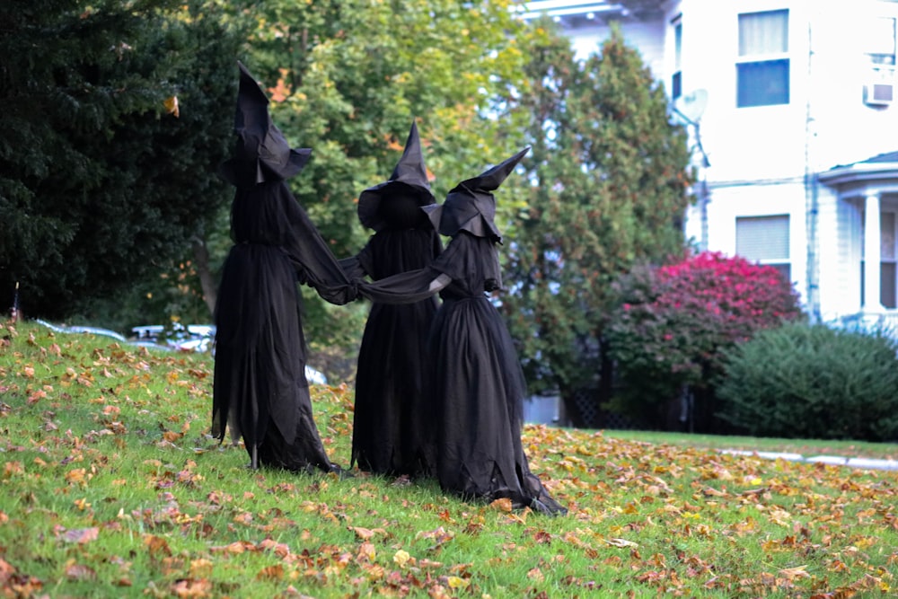 two people dressed in black holding hands in front of a house