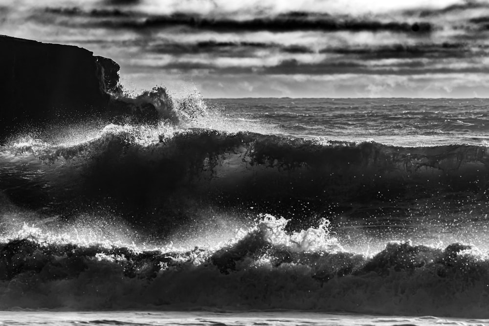 a black and white photo of a wave crashing