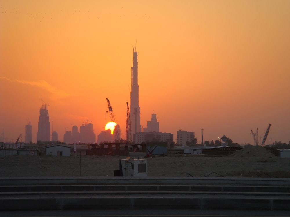 the sun is setting over a city with tall buildings