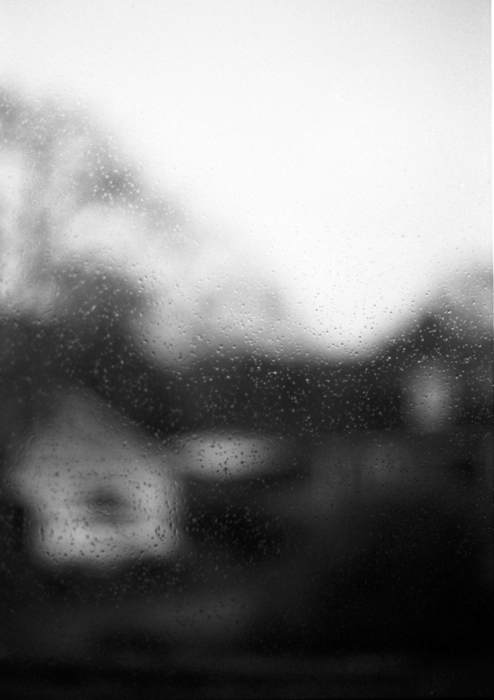 a black and white photo of a rainy window