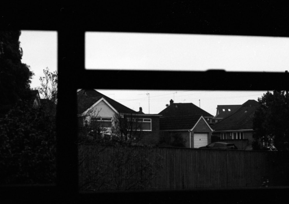 a black and white photo of a fence and houses