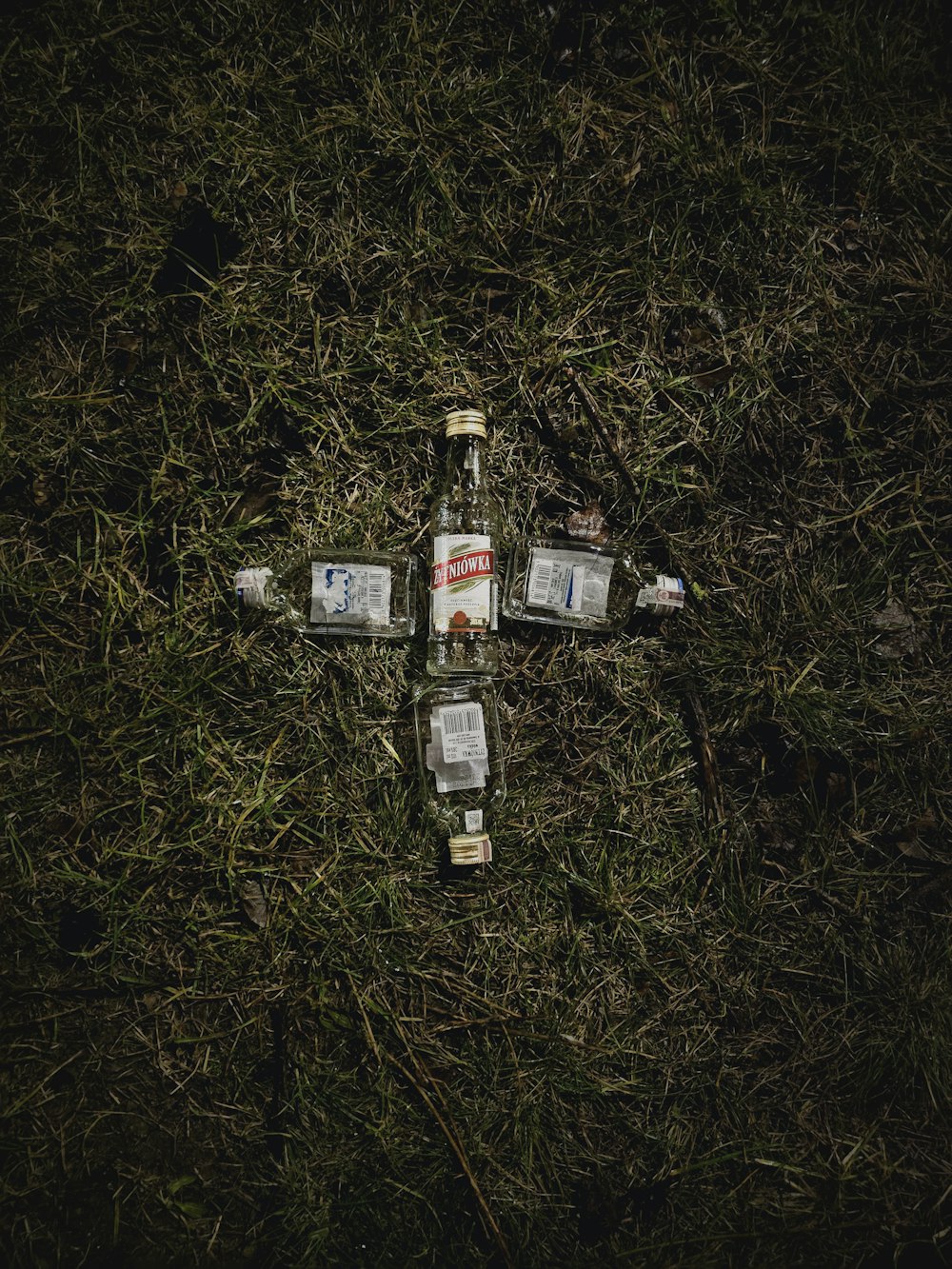 a cross made out of empty bottles on the ground