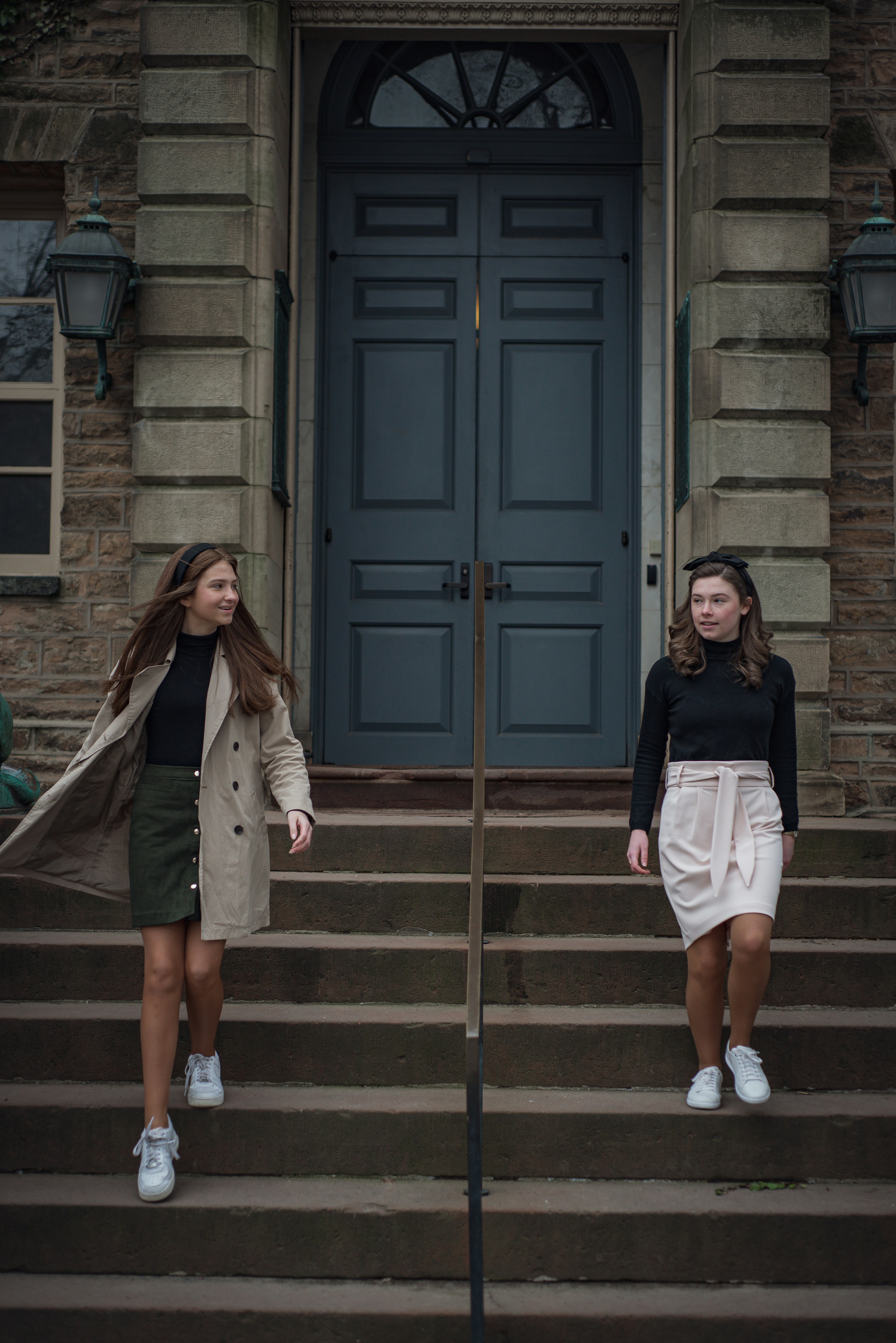 two women standing on steps in front of a building