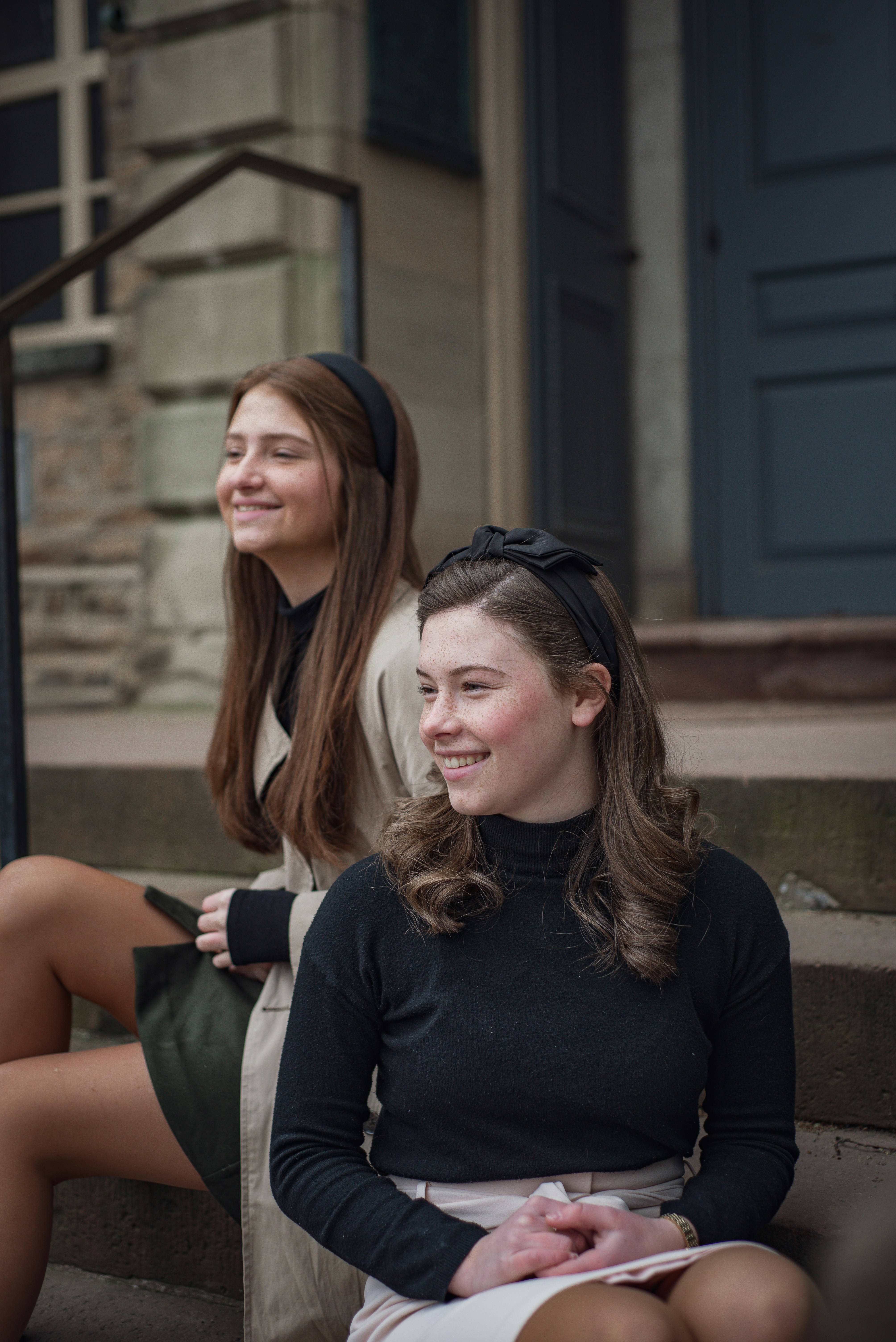 two women sitting on the steps of a building