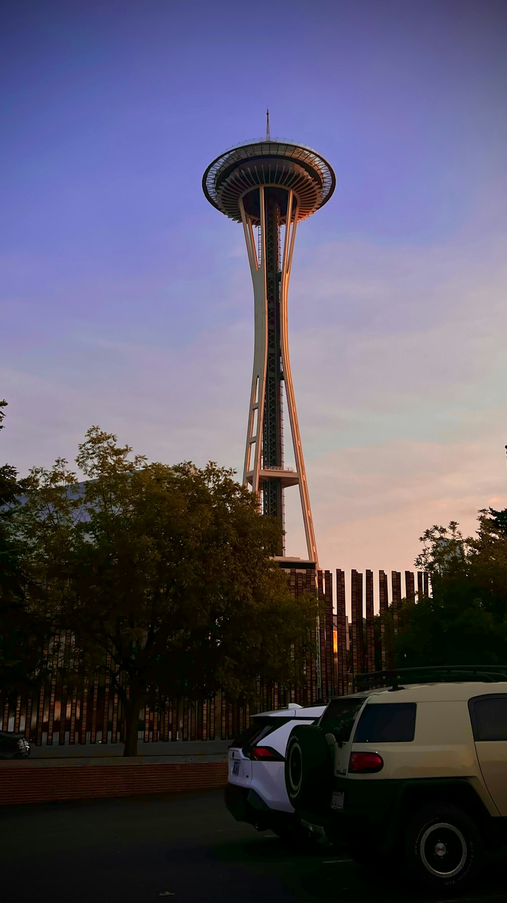 the space needle at sunset with cars parked in front of it