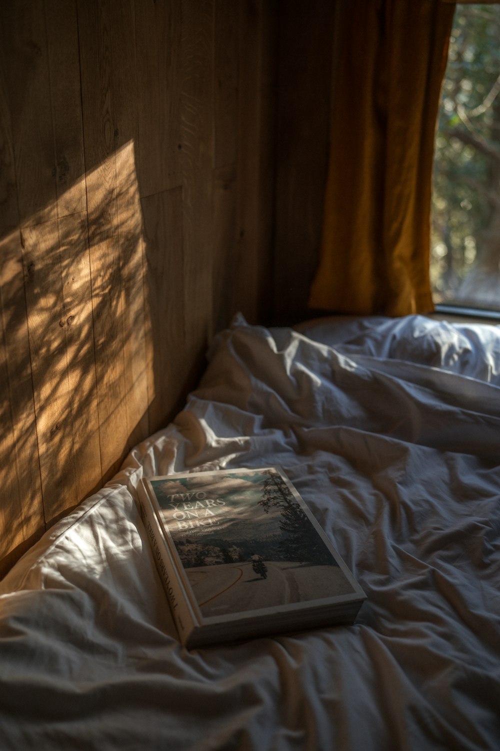 a book sitting on top of a bed next to a window