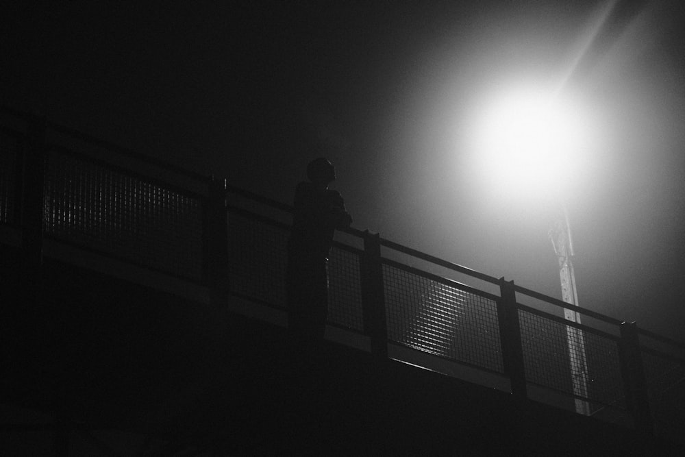 a person standing on a bridge at night