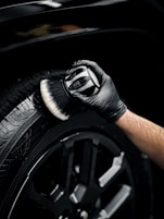 a man with a glove on his hand is polishing the tire of a car