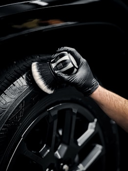 a man with a glove on his hand is wiping the tire of a car