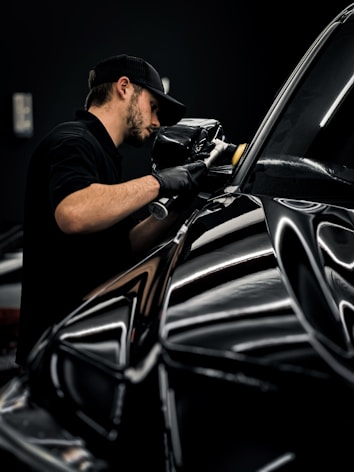 a man polishing a black car in a garage