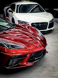 a red sports car parked next to a white sports car