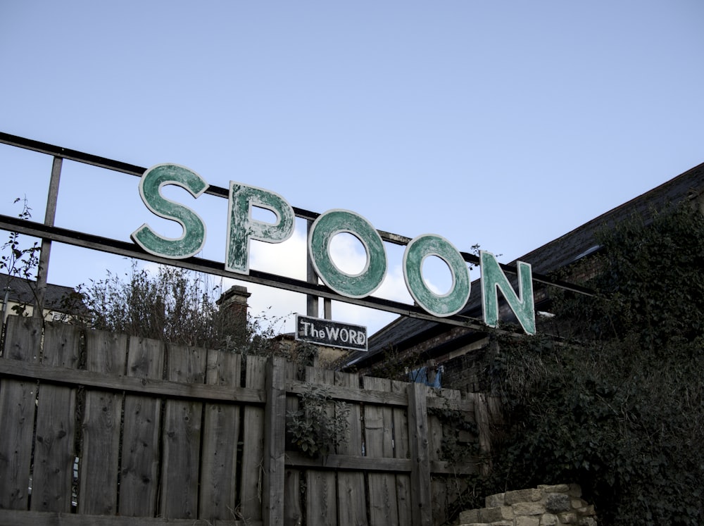 a sign that reads spoon above a wooden fence