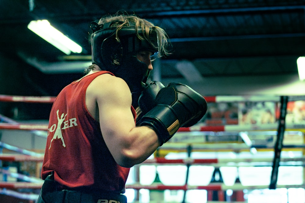 a man in a boxing ring wearing a red shirt and black boxing gloves