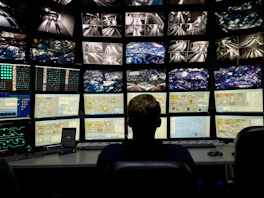 a man sitting in front of multiple monitors