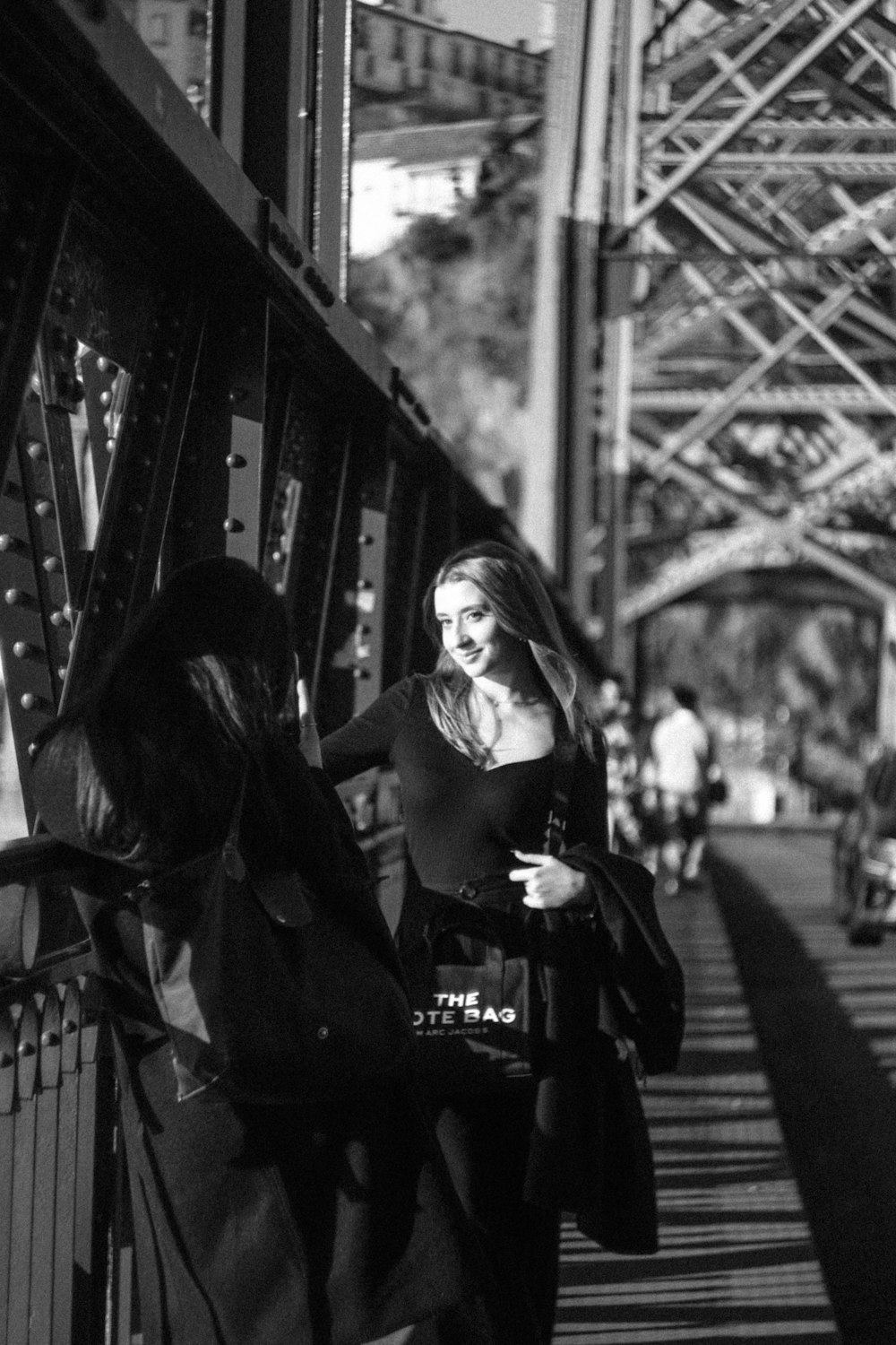 a black and white photo of two women on a bridge